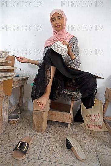 Moroccan woman painting bowls in the workshop