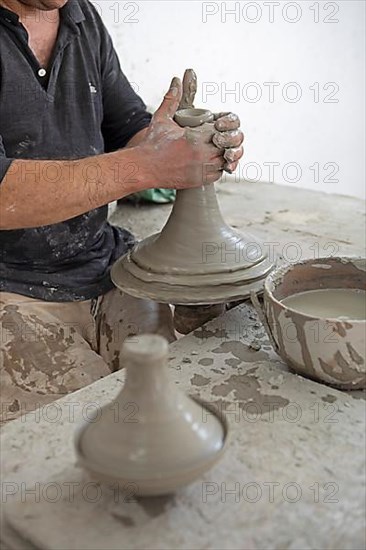 Moroccan potter at work: turning at the potter's pane and shaping ceramic vessels and pottery: Jugs