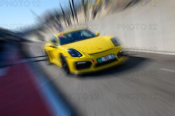 Dynamic photo with zoom effect of sports car racing car yellow Porsche Cayman GT4 leaving pit lane