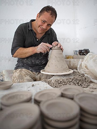 Moroccan potter at work: turning at the potter's pane and shaping ceramic vessels and pottery: Jugs