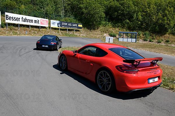 Two sports cars in front red Porsche Cayman GT4 with rear spoiler in the background Porsche 911 996 Carrera on course of driving safety training