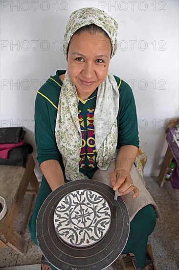 Moroccan woman painting plates in the workshop