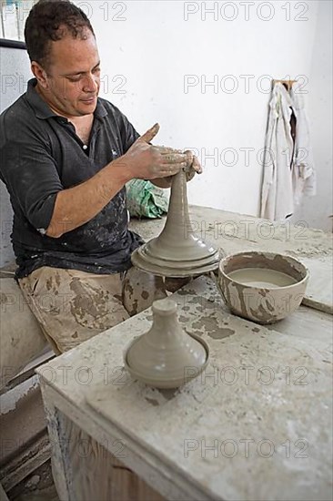 Moroccan potter at work: turning at the potter's pane and shaping ceramic vessels and pottery: Jugs