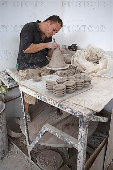 Moroccan potter at work: turning at the potter's pane and shaping ceramic vessels and pottery: Jugs