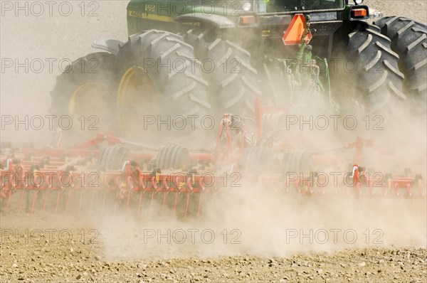 Close-up of tractor pulling harrows