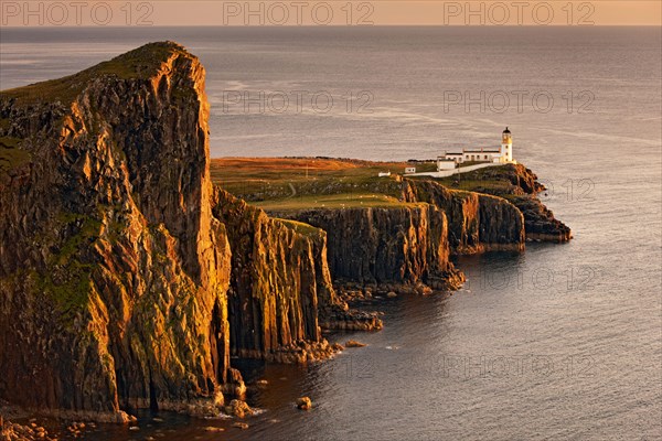View of sea cliffs and lighthouse at sunset