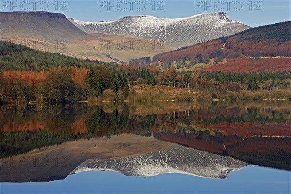 Trees and snow-capped hills reflected in the reservoir
