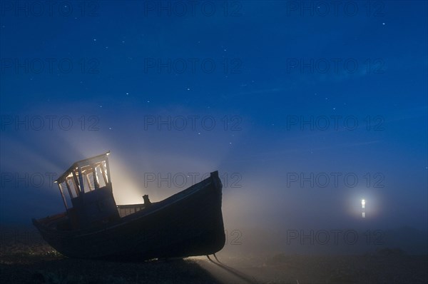 Abandoned fishing boat on a shingle beach at night