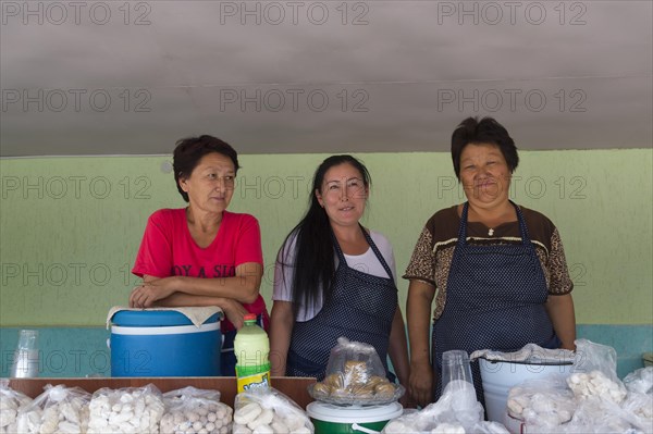 Group of Kazakh woman behind their stand with goat cheese and kumis