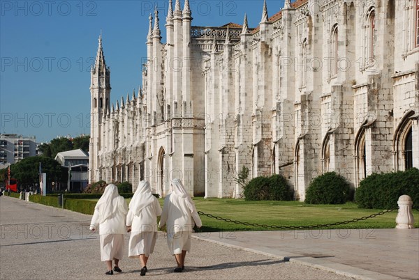 Three nuns walking outside late-Gothic Monastery