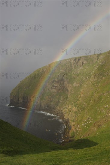 View of double rainbow over coastal cliff habitat