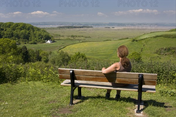 Woman sitting on bench overlooking the coast