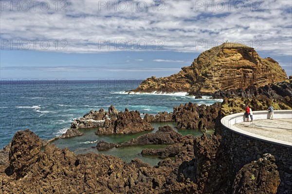 Tourists look from viewing platform at natural lava pools for bathing