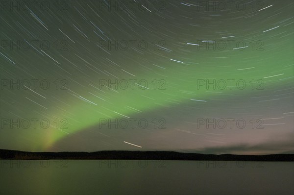 Aurora Borealis and star trails over the lake at night