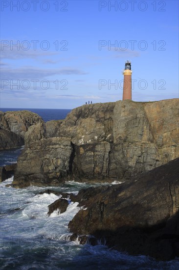 View of coastal cliff with lighthouse and tourists