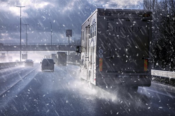 Cars and trucks driving on the motorway in sleet cause dangerous wet road conditions in winter