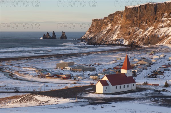 Reynisdrangar sea stack and Vik church in Vik i Myrdal village in winter