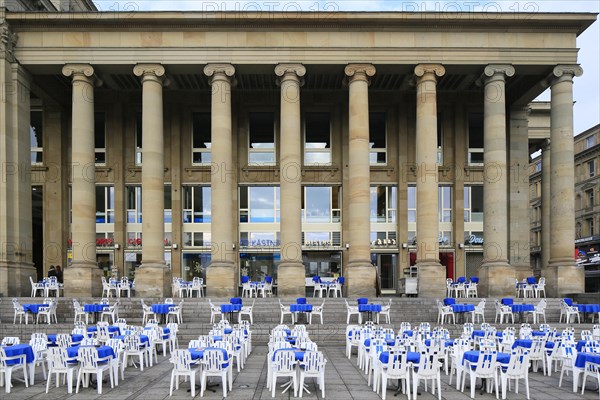 Tables and chairs of a street cafe in front of the Koenigsbau on Schlossplatz