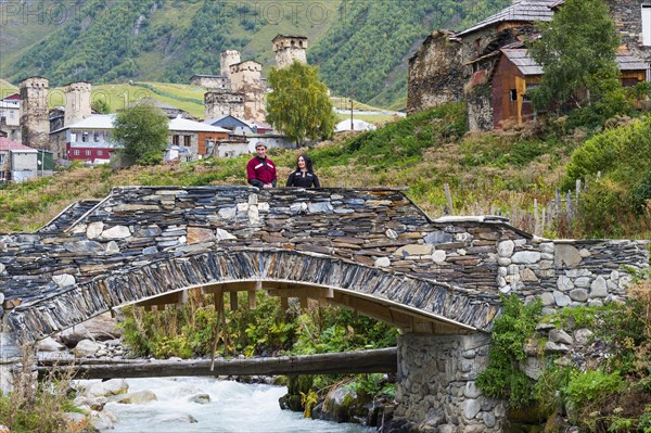 Georgian couple from a folklore group on a stone bridge outside the village of Ushguli