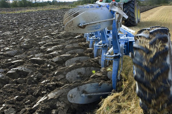 Close-up of a tractor-drawn eight-furrow reversible plough ploughing stubble fields