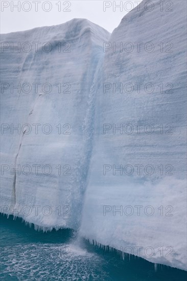 Coastal glacier terminus with waterfall from melting ice