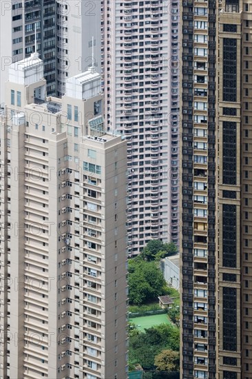 View of small garden and tennis court between skyscraper apartment blocks in densely populated urban area