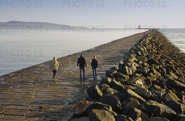 People walking on seawall protecting harbour entrance