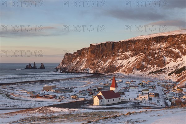 Reynisdrangar sea stack and Vik church in Vik i Myrdal village in winter