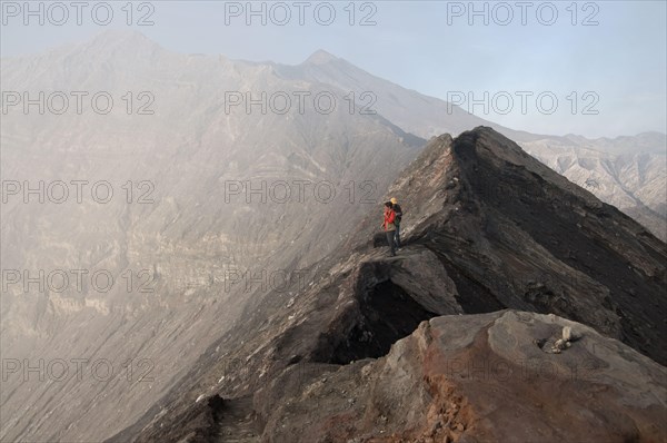 Tourists standing on edge of volcanic crater