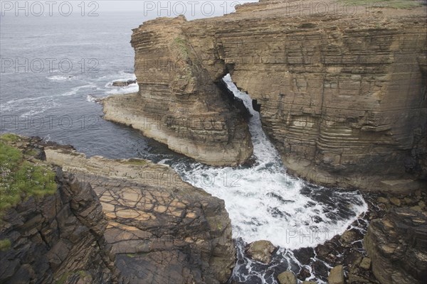 View of sea cliffs with water flowing through sea arch
