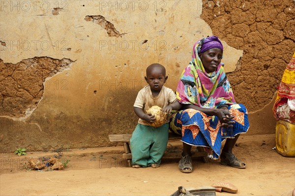 Woman and child sitting on a stool in front of the house