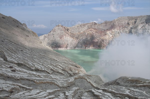 Turquoise-green coloured acidic volcanic crater lake with steam rising from its vent