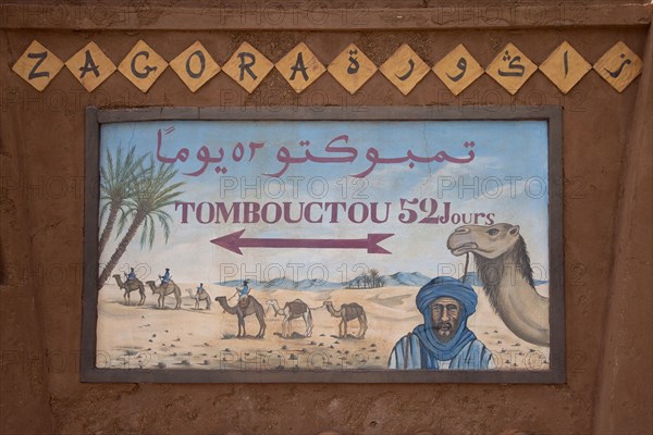 Signpost 'Tombouctou 52 days' in desert town