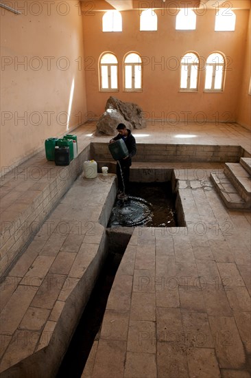 Man scooping water at Moses Spring