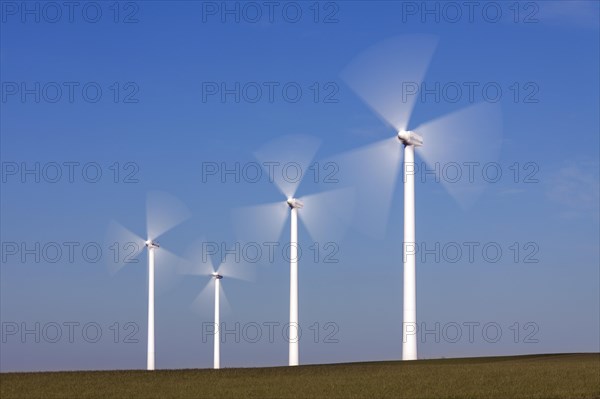Spinning blades of wind turbines at the wind farm against blue sky