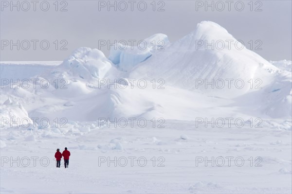 Two tourists walking on the ice of the frozen sea
