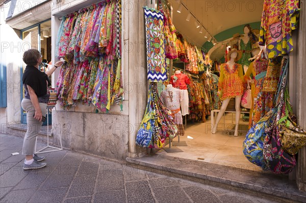 Older woman looking at and examining typical Sicilian fabrics and dresses