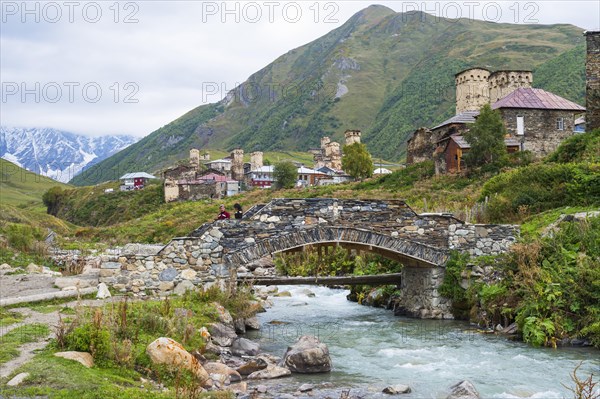 Georgian couple from a folklore group on a stone bridge outside the village of Ushguli