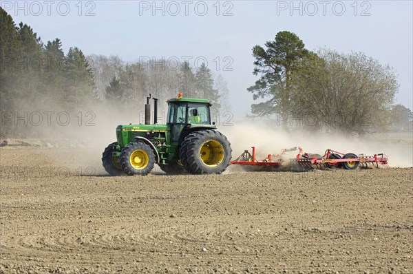 John Deere tractor pulling harrows