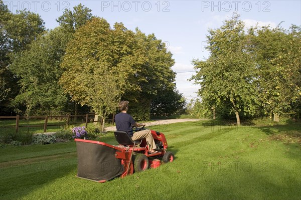 Use of a petrol-driven tractor lawnmower to mow garden lawns with grass catcher box