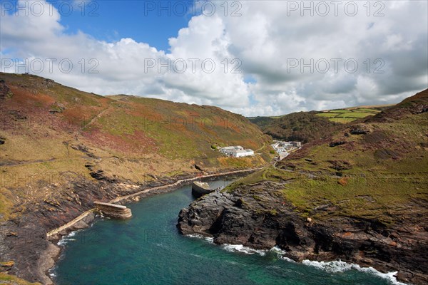 View of the coastline with breakwater and the old quay in the foreground leading to the village in the valley