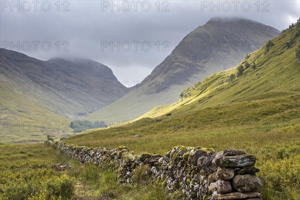 Old dry stone wall in moorland leading to the mountain Bidean nam Bian and the famous Three Sisters of Glen Coe