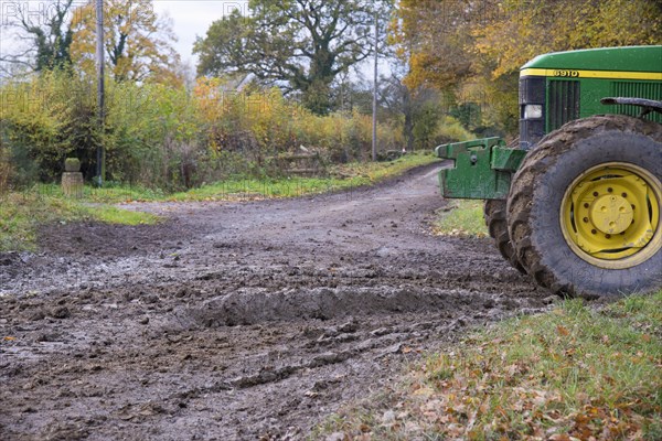 John Deere tractor beside muddy country road