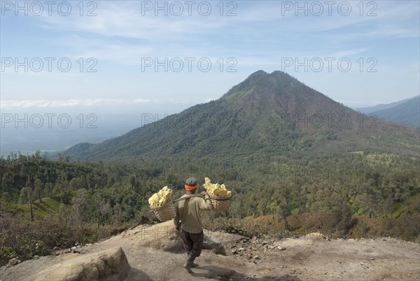 Local man carrying sulphur blocks in baskets down from the crater