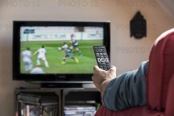Man with remote control in front of TV