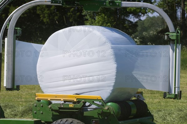 Plastic wrapping round silage bales with mechanical bale wrapper