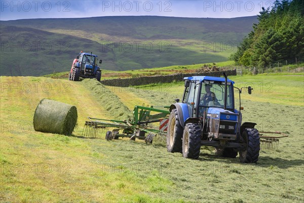 Tractors rowing and baling hay in the field