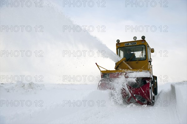 Snow blower clearing side road covered in drifting snow