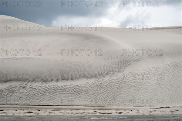 View of coastal sand dunes and beach at edge of lagoon