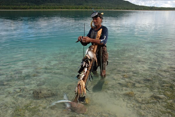 Spearfishermen standing in the sea with catches of reef octopus